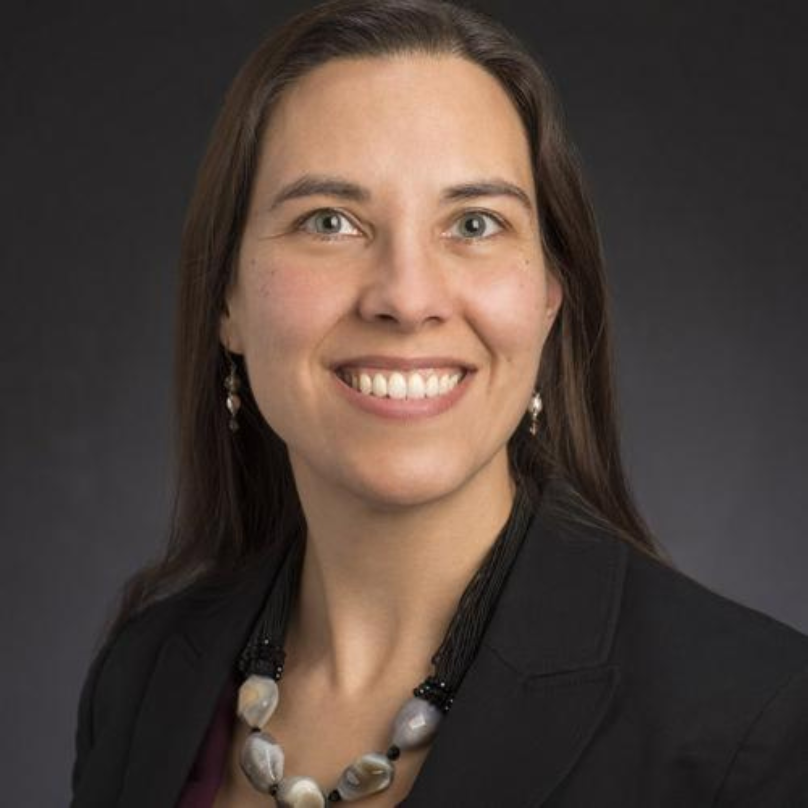 Portrait of Elizabeth Hoiem in a black suit jacket with a beaded necklace.