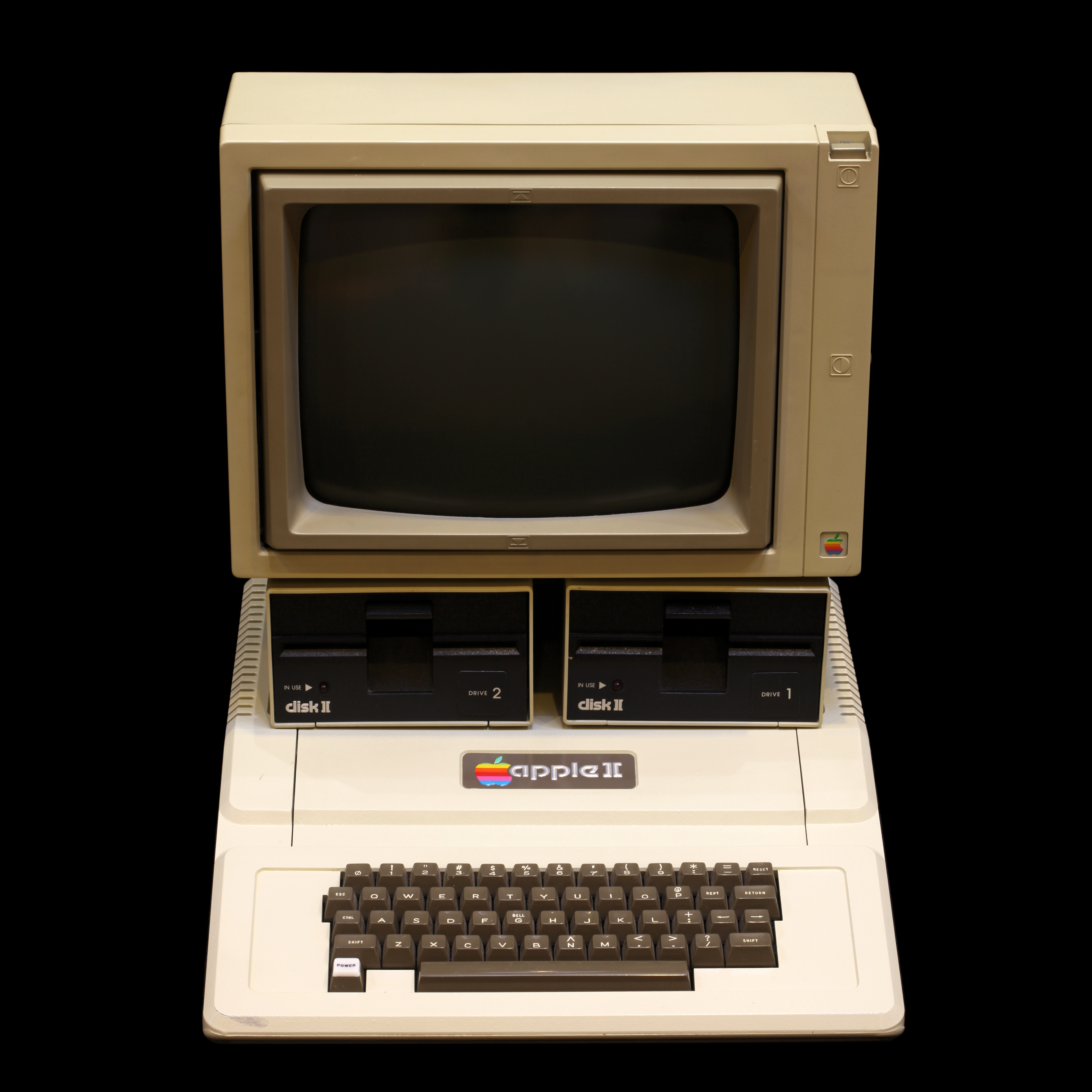 Photograph showing an Apple II computer, with the screen, keyboard, and disk ports visible.