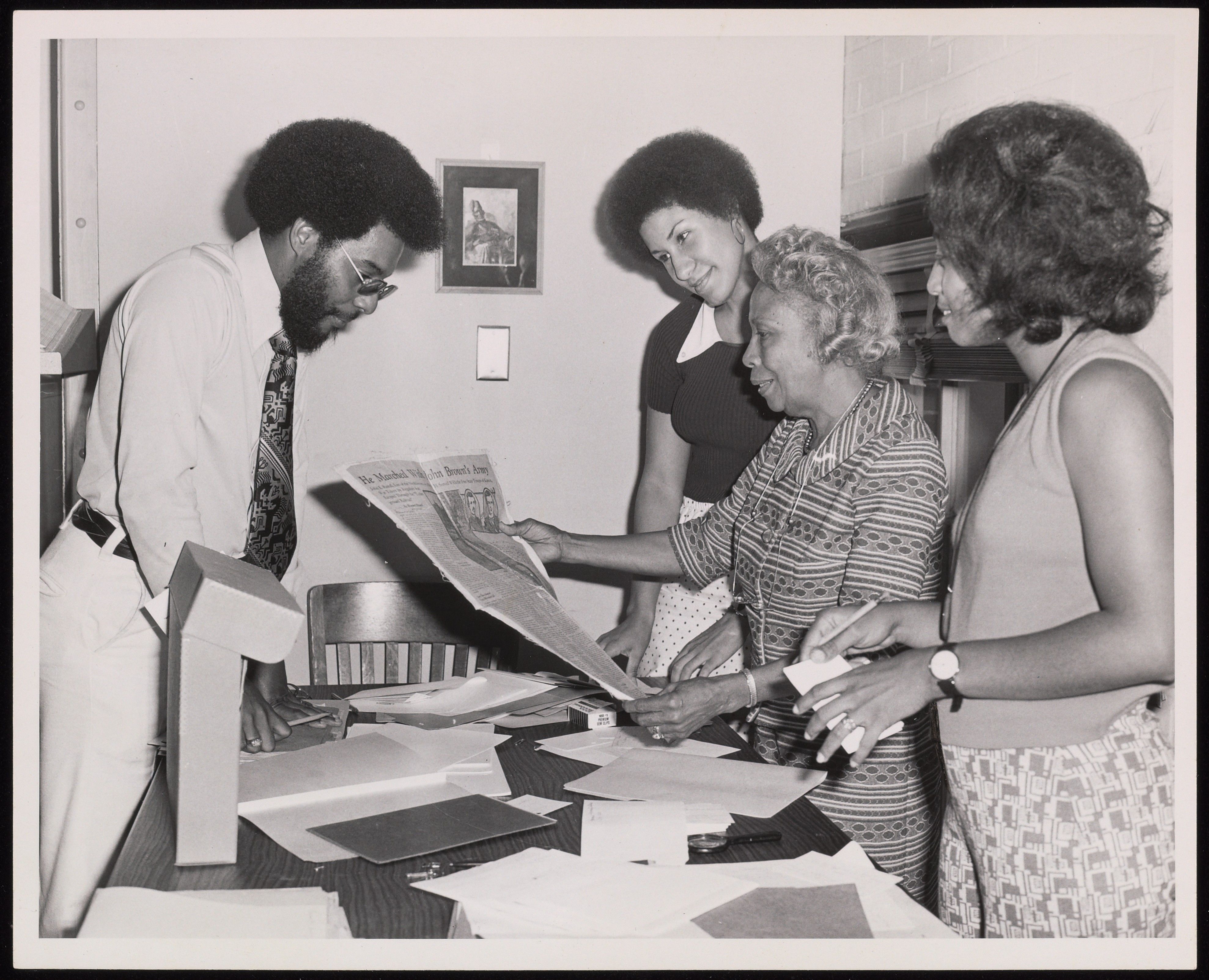Photograph of Dorothy Porter Wesley instructing manuscript staff: Thomas Battle, Evelyn Brooks-Barnett and Denise Glelin, Howard University